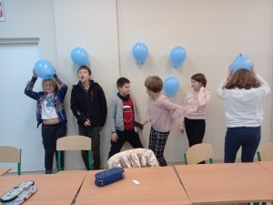 uczniowie przyczepiąją naelektryzowane balony do ściany