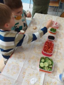 dzieci przy stole ze zdrowymi produktami warzywnymi. robią kanapki