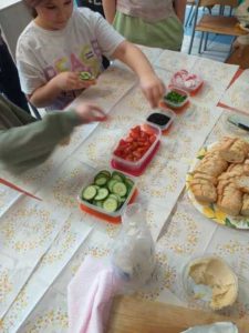 dzieci przy stole ze zdrowymi produktami warzywnymi. robią kanapki